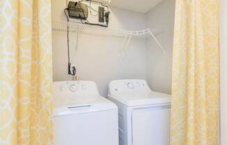 Two white washing machines in a small laundry room.