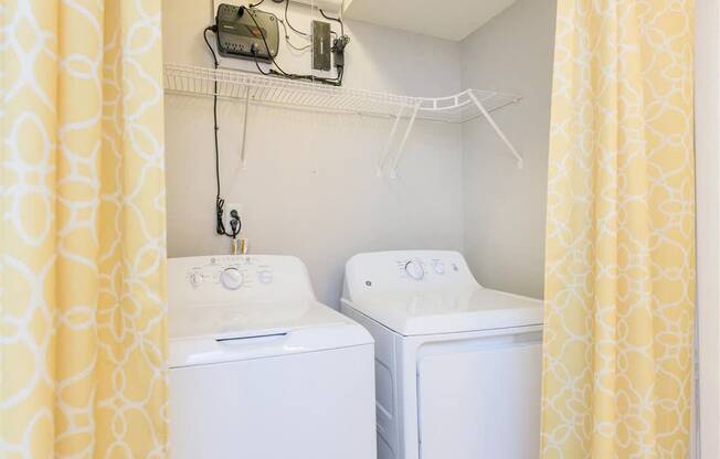 Two white washing machines in a small laundry room.