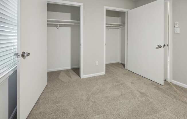 an empty bedroom with two closets and a carpeted floor