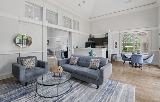 Resident lounge with grey couches, a glass coffee table, and a gray rug at Jefferson Place Apartments in Irving, TX