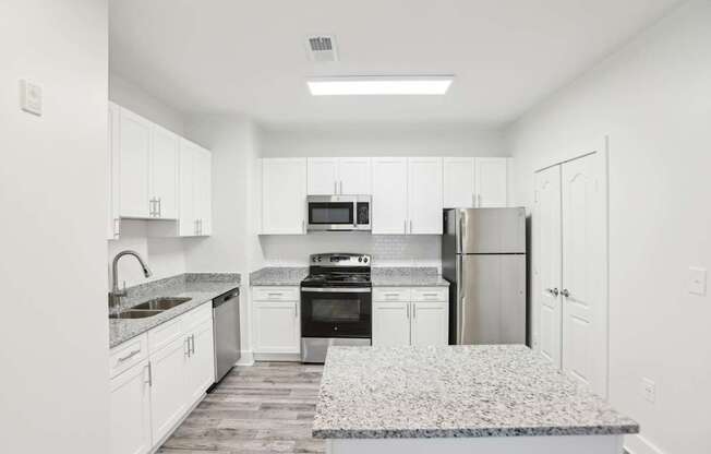 A kitchen with white cabinets and a granite countertop.
