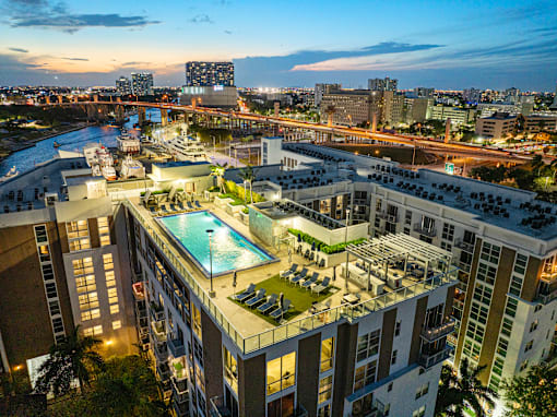 an aerial view of a hotel with a swimming pool and a city at dusk