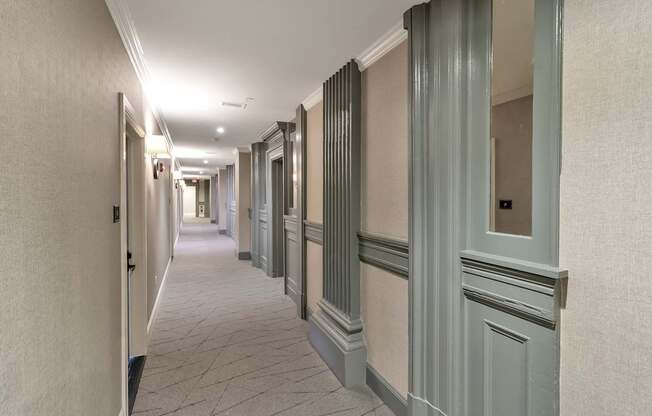 a long hallway with gray doors and white walls at The Knights @ 506 Delaware Apartments, Buffalo, New York