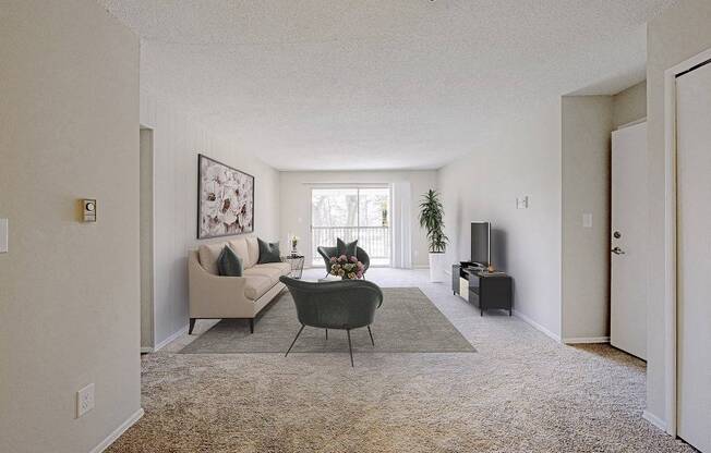 A living room with a couch, chair, and potted plant.