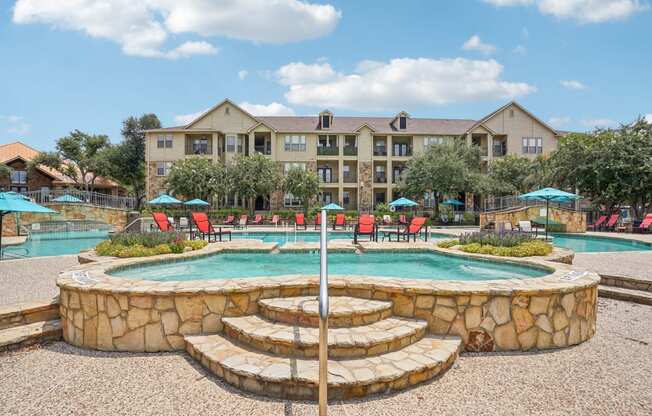 a swimming pool with a fountain and a hotel in the background at The Verandah, Austin, TX, 78726