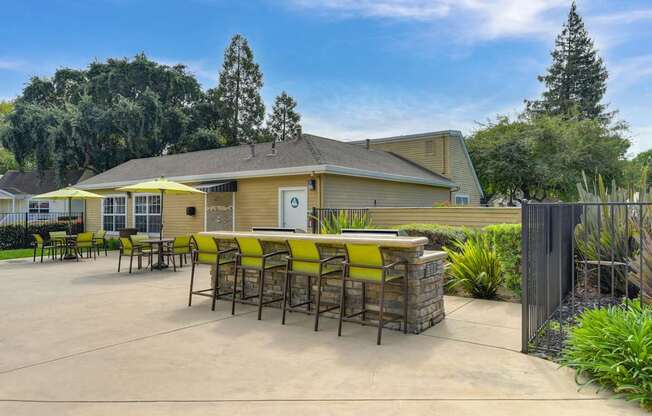 A yellow and brown building with a patio and chairs.