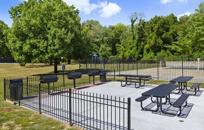 A black iron fence surrounds a picnic area.