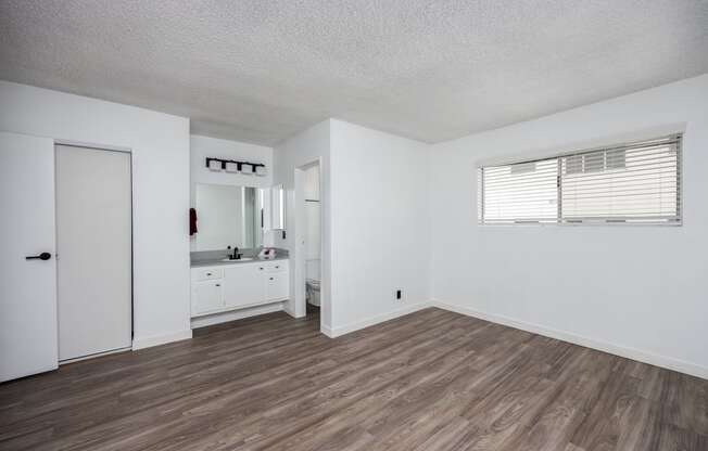 the living room of an apartment with white walls and wood flooring