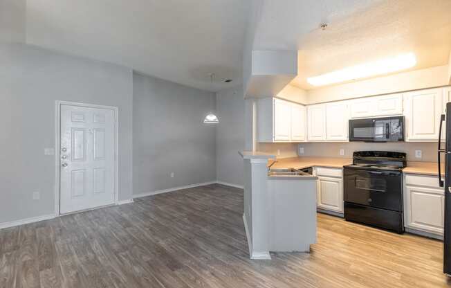 an open kitchen and living room with a wood floor and white cabinets