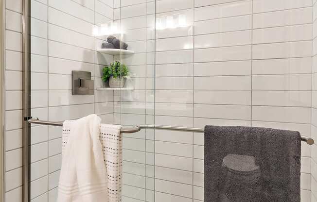 a small bathroom with white tiles and a glass shower door at The Griffin Royal Oak, Royal Oak, MI