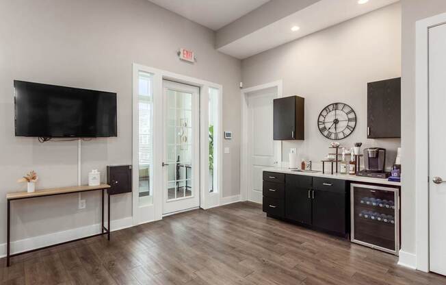A kitchen with black cabinets and a wooden floor.