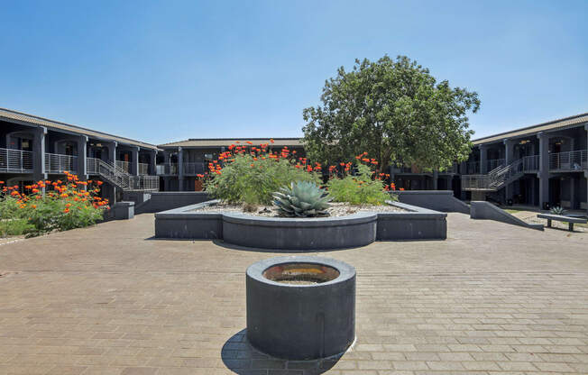 a courtyard with a fountain and plants in front of a building