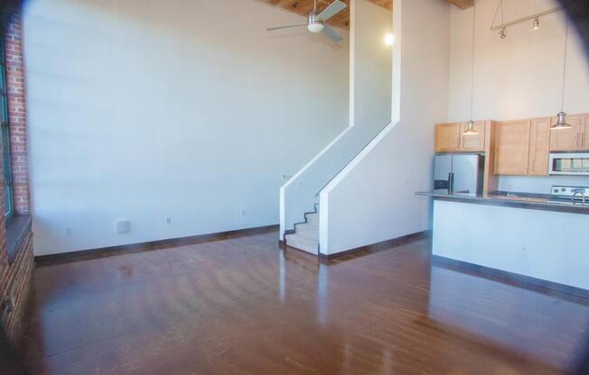 A room with a staircase and a kitchen area.