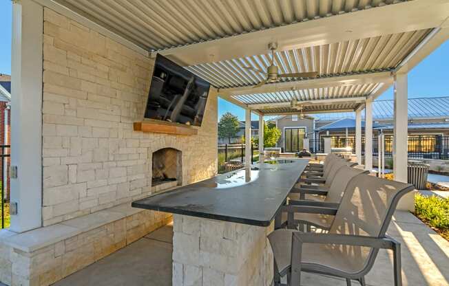 the outdoor patio has a fireplace and a long table with chairs at Crossgates Apartment Homes, Starkville, MS 39759