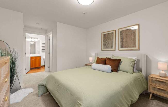 A bedroom with a bed, nightstands, and two framed pictures on the wall.
