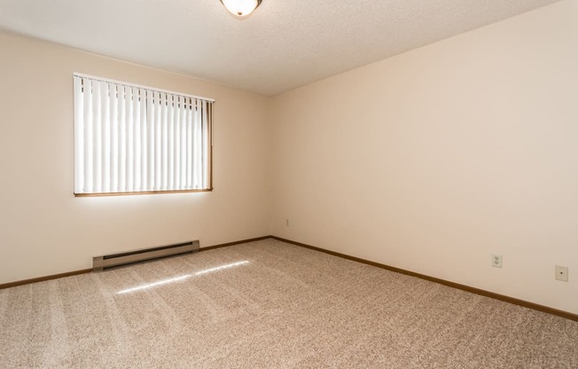 Grand Forks, ND Richfield Apartments. A bedroom with a window and carpeted floors