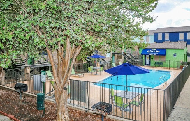 a swimming pool and a tree in front of a fence