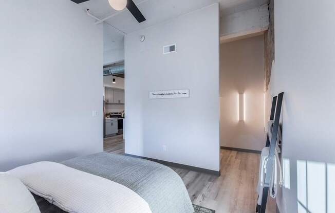 A white bedroom with a bed and a ceiling fan.
