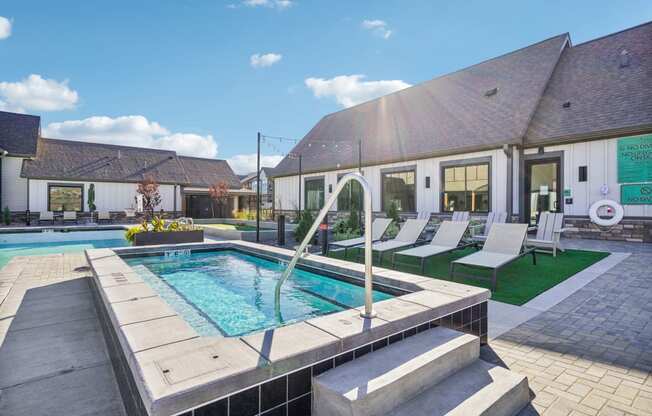 a swimming pool in front of a house with a pool and lounge chairs
