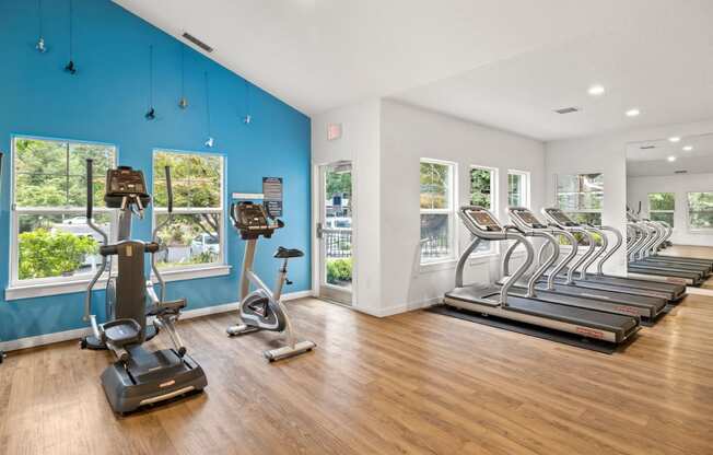 the gym with cardio machines and windows at the district flats apartments