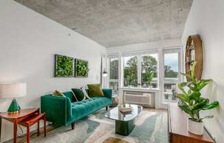 a living room with a green couch and a large window