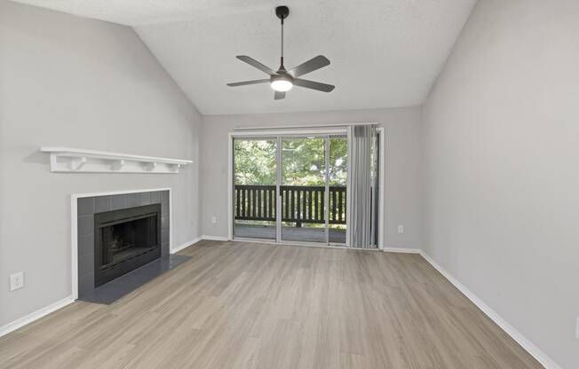 an empty living room with a fireplace and a ceiling fan