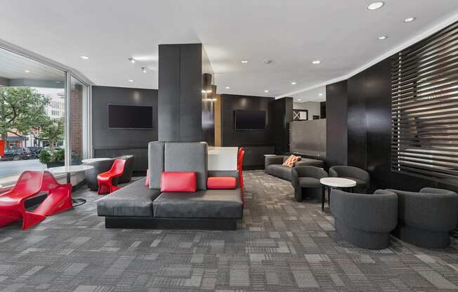 A modern lounge area with red and grey seating.