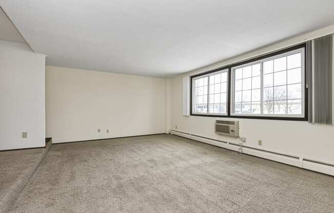 the living room of an empty house with a large window. Fridley, MN Georgetown on the River Apartments