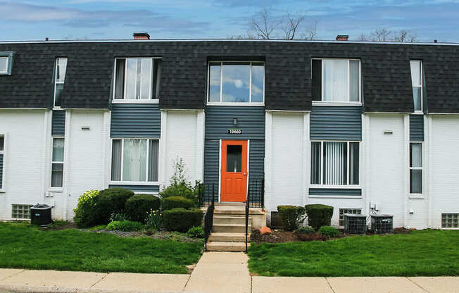 A white house with a black roof and a red door.
