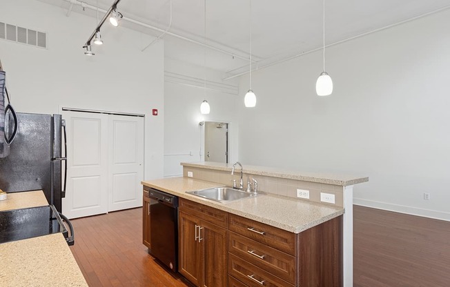 A kitchen with a sink, cabinets, and a refrigerator.