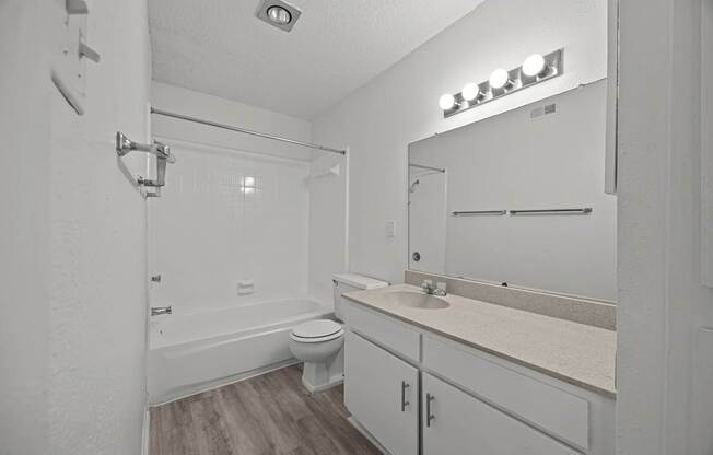 A white bathroom with a toilet, sink, and mirror.