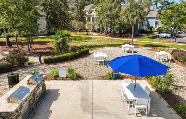 A blue umbrella is on a table in the middle of a courtyard.