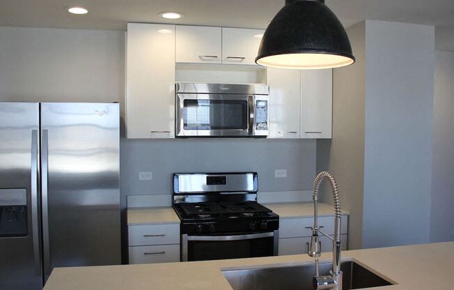 kitchen with modern pendant lighting quartz counters and white cabinets at Thomas Jefferson Tower, Birmingham, Alabama