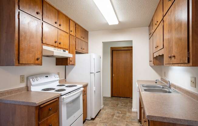 an empty kitchen with a stove refrigerator and sink. Fargo, ND Betty Ann Apartments