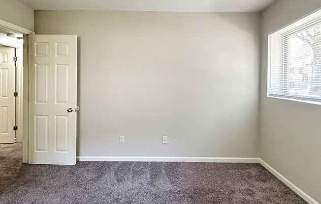 A room with a white door and a window with blinds.