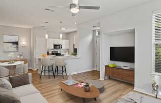 a spacious living room with a kitchen in the background and a ceiling fan in the foreground