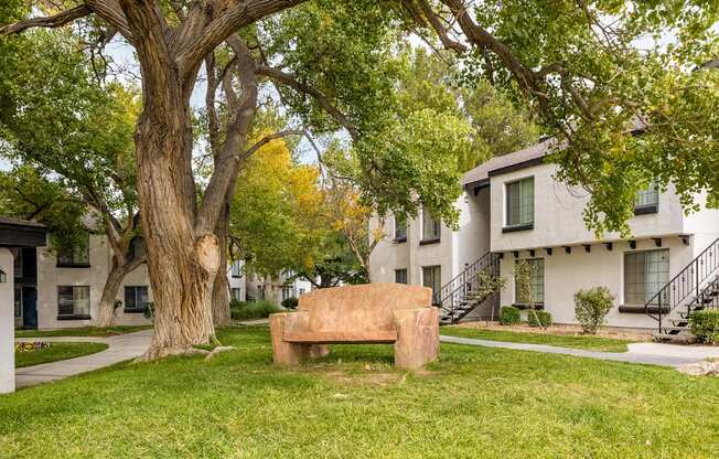 a stone bench sitting in the grass in front of houses