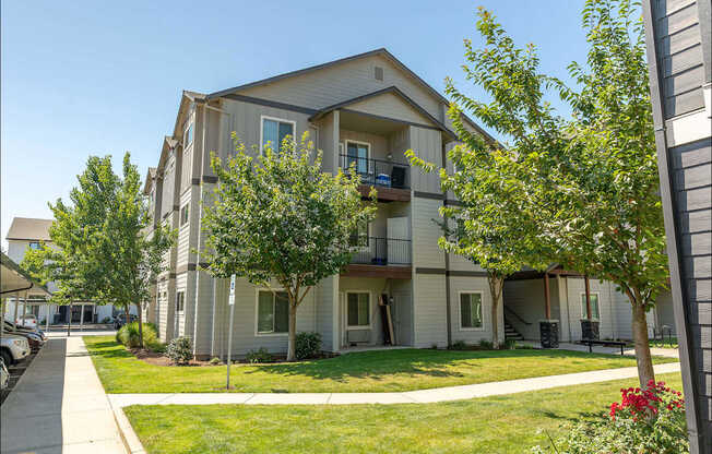 Apartment building with green trees and bushes in front at Forestplace Apartment Homes, Forest Grove, Oregon