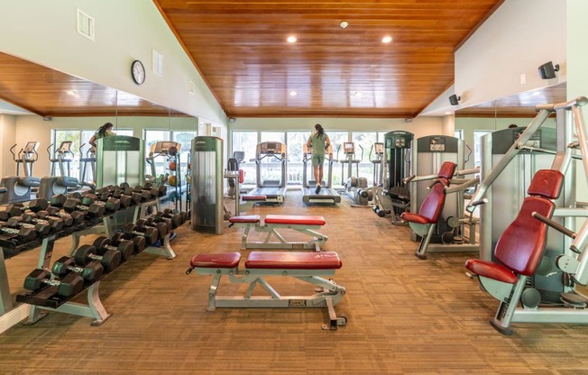 a gym with cardio equipment and a man standing in the window