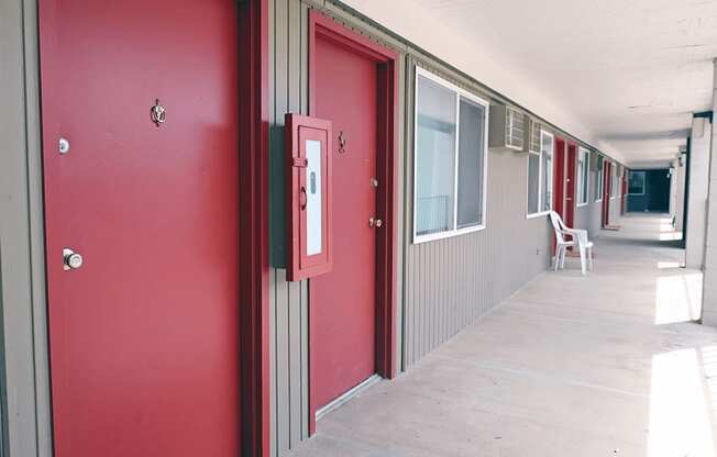 A long hallway with red doors and white walls.