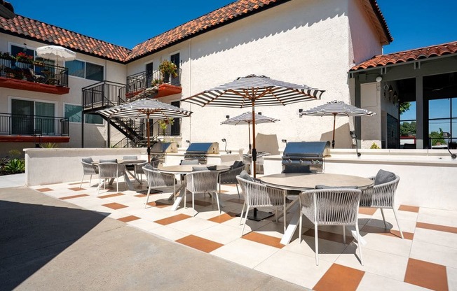 A patio with a table and chairs under umbrellas.