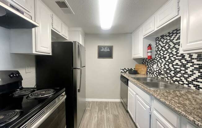 a kitchen with white cabinets and black appliances  at 2151 Kirkwood, Texas