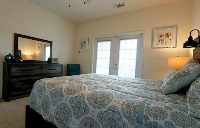A bedroom with a bed, dresser, and mirror.
