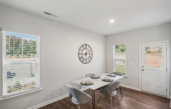 a dining room with a table and chairs and a clock on the wall