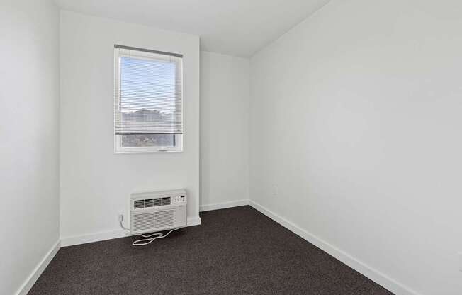 A room with a window and a fan on the floor.