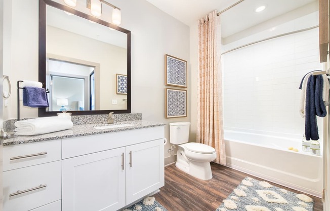 Bathroom with wood-designed flooring, large vanity counter, and shower/tub at The Highland