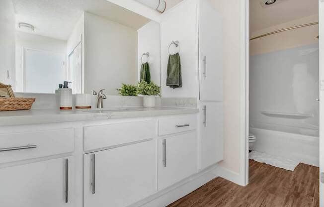 a white bathroom with a large mirror and white cabinets