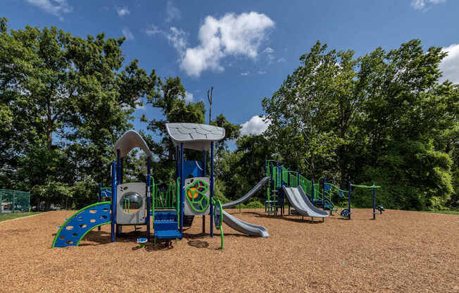 A playground with a blue slide and a green slide.