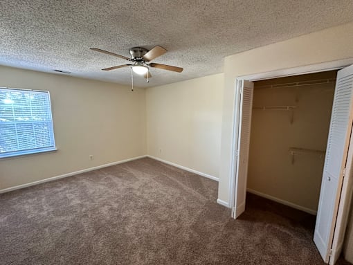an empty bedroom with a ceiling fan and a closet