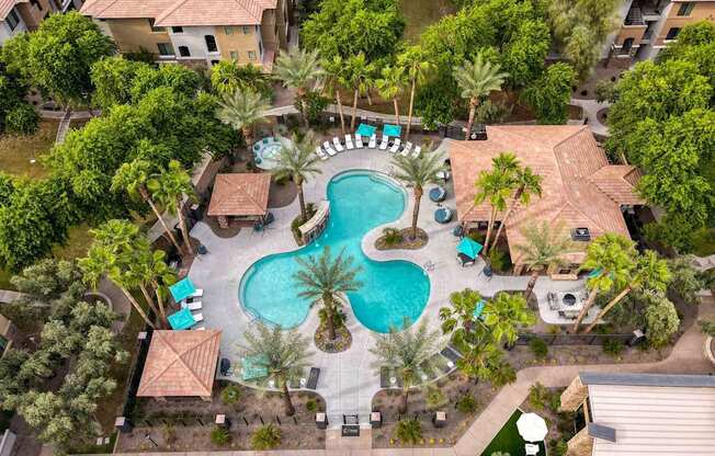 A pool surrounded by palm trees and a patio area. at The Laurel Apartments, Chandler, AZ 85286